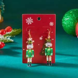 Detail shot of green nutcracker acrylic earrings on festive red display card.