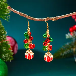 Nahaufnahme von festlichen Weihnachtsohrringen mit roten Glocken und Geschenkboxen