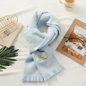 Detailed view of light blue plaid winter warm scarf with cute bear label and fringes.