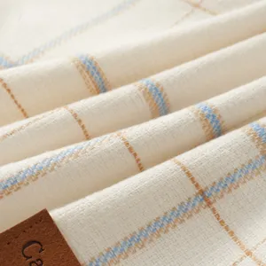 Detail van de geruite sjaalstof met zachte textuur en klassiek ruitjespatroon in crème en blauw.
