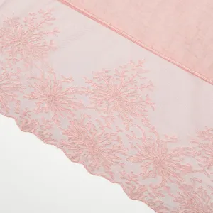 Gedetailleerde close-up van een roze katoen-linnen sjaal met fijne kanten bloemenborduursel.