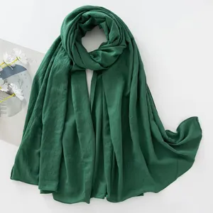 Dettaglio in primo piano della sciarpa stropicciata in rayon verde scuro, tessuto morbido.