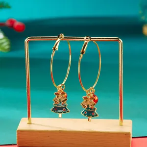Detail of gold hoop earrings with green Christmas tree charms on a display stand