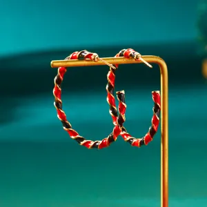 Detail of red and black twisted hoop earrings for Christmas on a gold stand