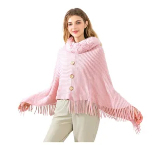 Detailed view of pink knitted poncho featuring a plush faux fur collar and fringe hem