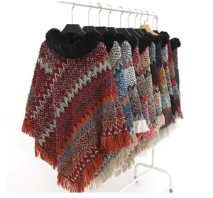 Warme Strickponchos mit Kunstfellkragen und Chevron-Mustern an einem weißen Kleiderständer