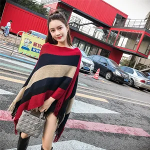Woman wearing a stylish striped knit poncho with irregular tassel hem in an urban setting
