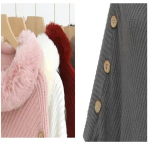 Detail of knitted poncho with faux fur collar and wooden buttons in multiple colors.
