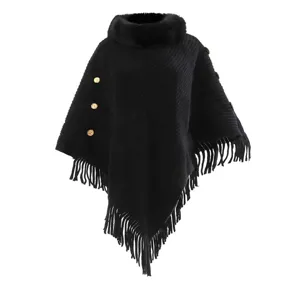 Detail shot of elegant black knitted poncho with faux fur collar and tassel fringe