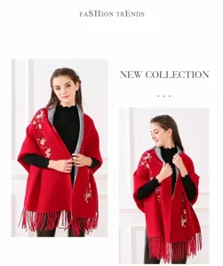 Detailansicht eines roten Strickschals mit zarter Blumenstickerei und Fransen