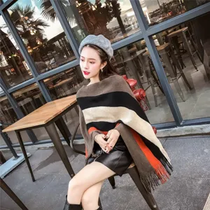 Detail of asymmetrical striped knit poncho with tassels in casual outdoor cafe setting