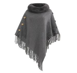 Close-up of a grey knitted poncho featuring a plush faux fur collar and fringe hem