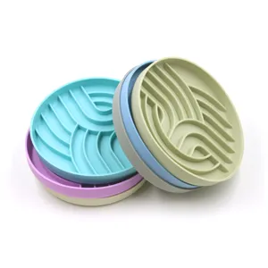 Detailed view of stacked colorful silicone slow feeder pet mats with maze-like patterns.