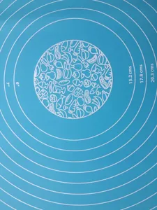 Thick silicone baking mat detail view with concentric measurement circles and food icons.