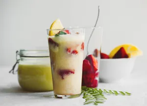 Verfrissende aardbei citroen fruit smoothie in een glas met verse ingrediënten en decoratie.