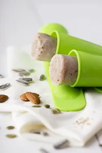 Green silicone ice cream mold detail view, flexible push up popsicle maker with lid