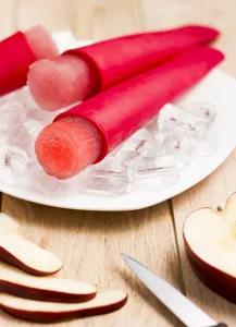 Silicone ice pop mold detail showing red cylindrical tube design on ice and plate.