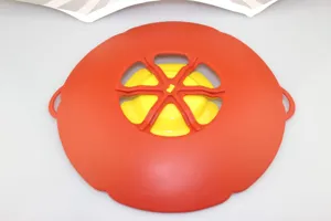 Vue détaillée du couvercle anti-débordement en silicone rouge et jaune résistant à la chaleur.