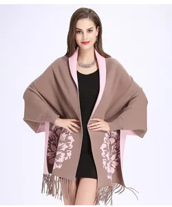 Detailansicht eines eleganten Jacquard-Ponchos mit Quasten und Ärmeln in Braun/Rosa