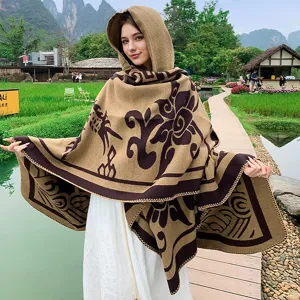 Model in einem braunen Strickumhang mit Kapuze und floralen Vintage-Mustern im Freien