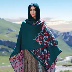 Close-up of a dark green jacquard hooded knitted poncho shawl worn in mountain scenery