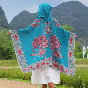 Detailansicht des petrolfarbenen Kapuzenponchos mit rotem Paisley-Jacquard-Muster