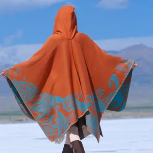 Back view of a hooded orange knitted poncho with intricate blue paisley embroidery details