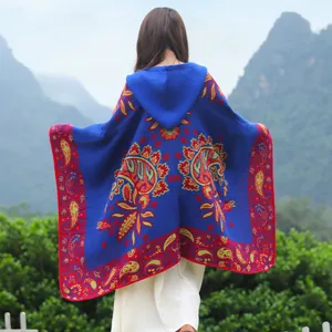 Rückansicht eines blauen Ponchos mit Kapuze und Paisleymuster in schöner Landschaft.