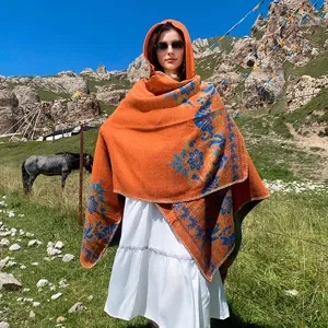 Detail of a hooded jacquard knitted shawl worn outdoors in a scenic mountain landscape