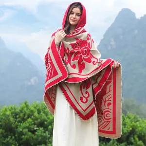 Detailansicht eines stylischen roten floralen Strickponchos mit Kapuze im Freien