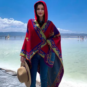 Detailansicht eines roten Damen-Kapuzenponchos mit ethnischen Mustern in Landschaft