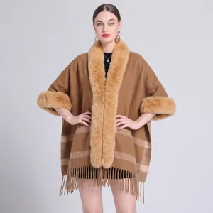 Detailansicht eines braunen Strickponchos mit Pelzkragen und Fransenbesatz.