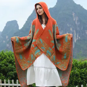 Frau trägt ein Paisley-Jacquard-Poncho mit Kapuze in einer malerischen Berglandschaft