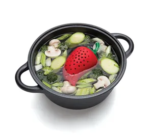 Silicone strawberry spice infuser detail view inside soup pot with fresh vegetables for cooking.