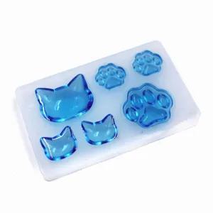 Close-up details of DIY blue cat head and paw resin pieces inside clear silicone mold.