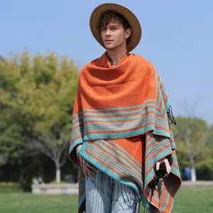 Stylish men's orange and teal striped knitted poncho with fringe in an outdoor setting