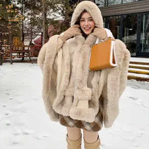 Cape à capuche élégante en fausse fourrure beige portée par un mannequin dans un décor de neige.
