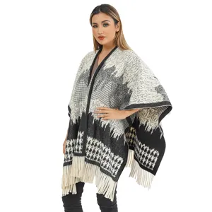 Detailed view of women's black and white houndstooth knit poncho with fringe tassels