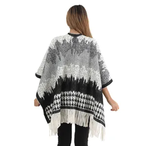 Detailed back view of a black and white houndstooth knit poncho with white tassels.