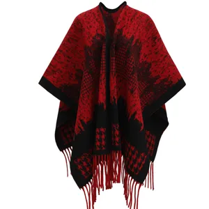 Detailed view of red and black houndstooth knit poncho with fringe tassels.
