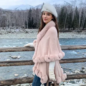 Close-up of pink knit poncho with luxury faux fur collar in a winter outdoor setting