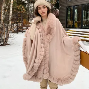 Elegant dusty pink winter fur-trimmed cape shawl shown in a snowy outdoor lifestyle setting.