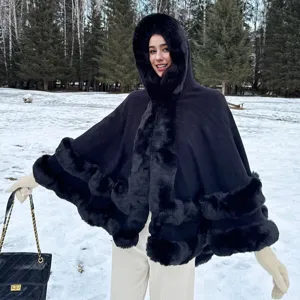 Élégant poncho en maille noir avec capuche et bordure en fausse fourrure dans un décor de neige