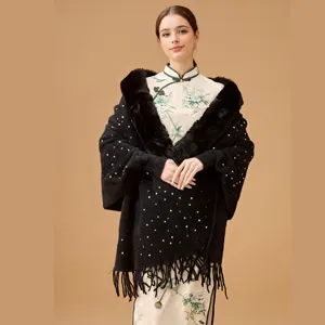 Elegant black knit shawl with sequins and faux fur collar worn by model against a warm background