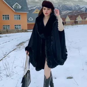 Detailed view of elegant black winter cape with oversized faux fur collar on snowy background