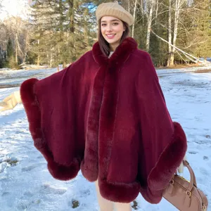 Cape élégante en tricot bordeaux avec bordure en fausse fourrure dans un décor de neige
