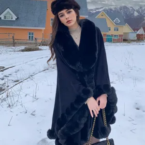 Elegant black faux fur trimmed cape shawl for women in snowy winter outdoor setting