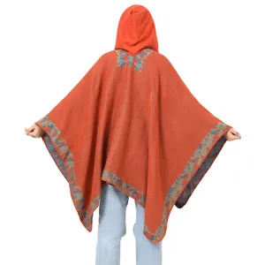 Vista trasera detallada de poncho bohemio naranja con capucha y dobladillo floral tejido
