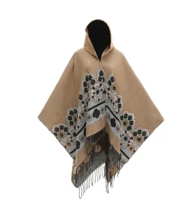 Detalle de un poncho de punto caqui con flores, capucha y flecos en la parte baja.