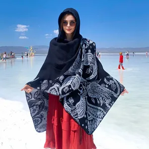 Elegant hooded knitted shawl with white folk bird pattern against a salt flat background.